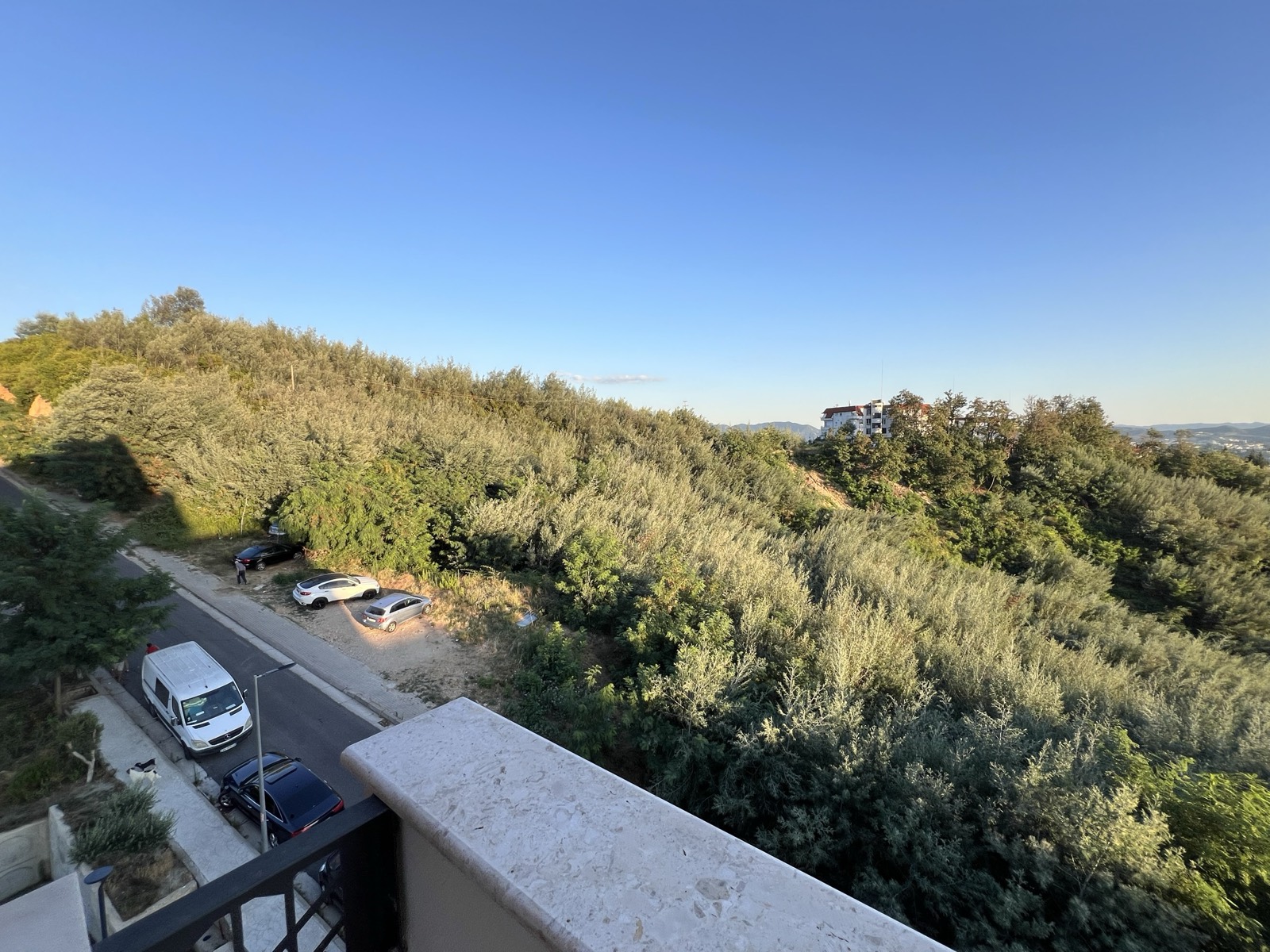 The quiet, tree-lined street below the apartment on the green edge of Fresku